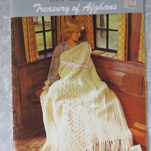 May include: A Bernat Treasury of Afghans pattern book, Book No. 246, featuring a cream-colored, textured, cable-knit afghan with fringe. The cover displays the title in white script and blue block letters, with a price tag of $4.00 in Canada.