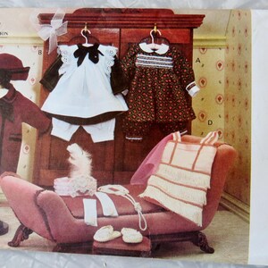 May include: A vintage sewing pattern for a doll dress, featuring a white dress with a lace collar and a brown dress with a floral print. The pattern is titled "Vogue Craft 8648" and includes instructions for making a doll dress in one size.