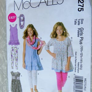 May include: McCall's M6275 sewing pattern for Girls Plus sizes. The pattern includes options for a dress, tunic, leggings, and scarf. The cover features illustrations of the finished garments, with the word "EASY" in a pink circle.
