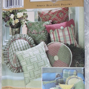 May include: A Simplicity Home sewing pattern envelope for pillows, featuring illustrations of various decorative cushions in plaid, floral, and solid fabrics with tassels, ruffles, and pom-pom trim. The package includes text labels and a barcode.