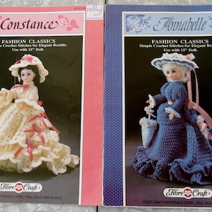 May include: Two vintage crochet doll pattern books, "Constance" and "Annabelle." The "Constance" pattern features a doll in a cream-colored dress with pink accents. The "Annabelle" pattern shows a doll in a blue dress with a matching hat and parasol.