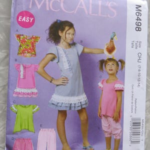 May include: McCall's sewing pattern M6498 for girls' clothing. The pattern includes options for tops, dresses, and pants. The package features illustrations of the finished garments in various colors and styles, with the word "EASY" in a red circle.