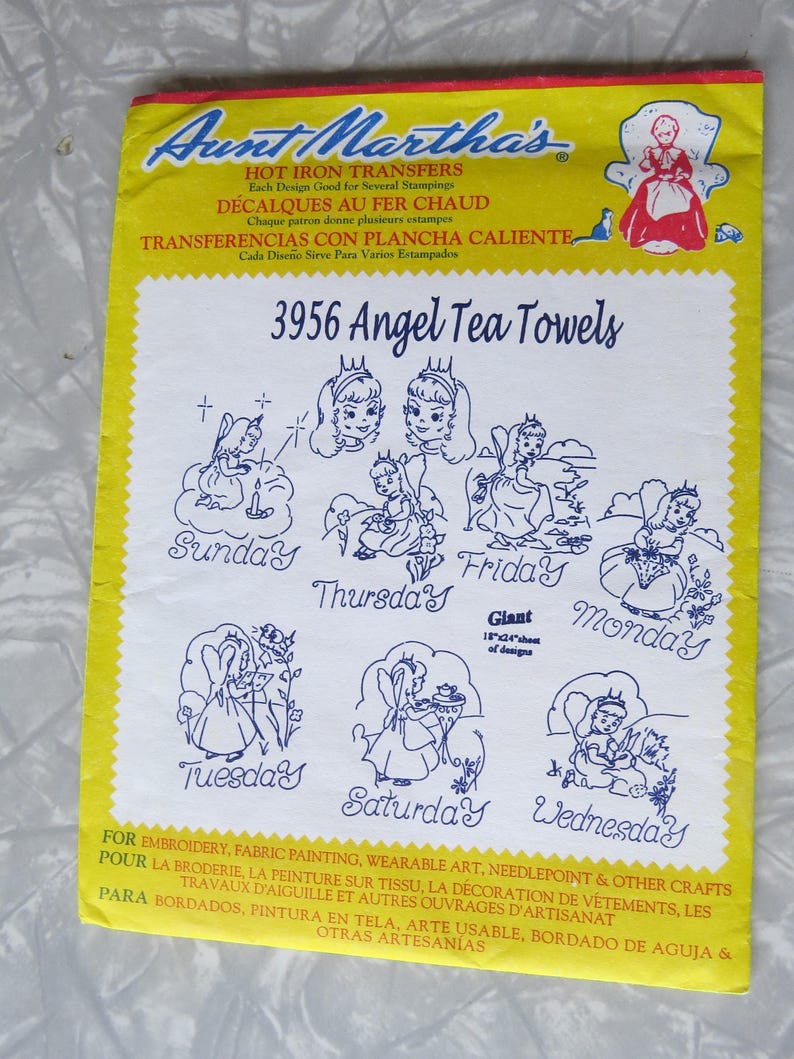 May include: A yellow and white Aunt Martha's iron-on transfer sheet for embroidery. The sheet features the text "3956 Angel Tea Towels" and illustrations of angels for each day of the week. The sheet is 45.7cm x 61cm.