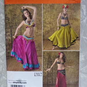 May include: Simplicity sewing pattern 2158, size HH 6, 8, 10, 12. The envelope displays three variations of a two-piece outfit featuring a cropped top and a long, flowing skirt with ruffled hems, shown in magenta, olive green, and dark red fabric.