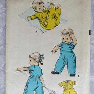May include: Vintage sewing pattern for a baby's one-piece outfit. The pattern is for size 1/2, with a 19-inch chest. The pattern shows three different views of the outfit, one in yellow and two in blue.