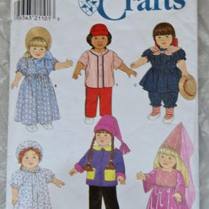 May include: A Simplicity Crafts sewing pattern for making doll clothes. The pattern includes five different outfits: a pink princess dress, a blue and white sailor dress, a red and white baseball uniform, a purple jacket with yellow pockets, and a floral print nightgown.