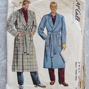 May include: Vintage McCall printed pattern for men's and youth's robes. The illustration shows two men wearing robes, one in a plaid pattern and the other in blue. The pattern includes the size and style number.
