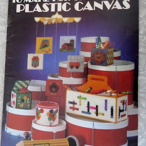 May include: A vintage craft book cover titled "Projects to Make for Children in Plastic Canvas." The cover features various finished plastic canvas projects, including boxes, a pencil, and a mobile. The color scheme is red, white, and blue.