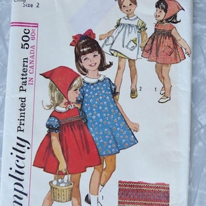May include: Vintage Simplicity sewing pattern 5948 for children's dresses, size 2. The illustration shows three girls in dresses, one in red with a basket, another in blue, and a third in white. The pattern is marked 50c in the US and 60c in Canada.