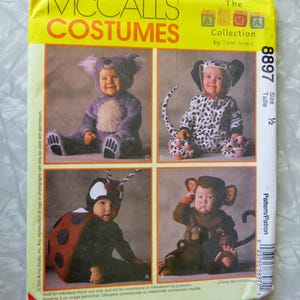 May include: McCall's Costumes 8897 sewing pattern envelope featuring The Alma Collection by Tom Arma. The yellow package displays four infant costume designs: a purple koala, a black and white dalmatian, a ladybug, and a brown monkey.