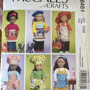 May include: McCall's Crafts sewing pattern M6451 featuring doll outfits. The pattern includes instructions for making doll clothes, including aprons, hats, and accessories. The dolls are dressed as an artist, chef, and more. The pattern size is OSZ.