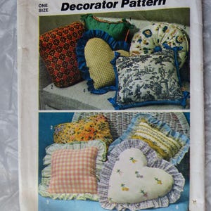 May include: A Simplicity 6483 sewing pattern envelope for decorator pillows. The cover displays various cushion designs including heart-shaped, round, and square pillows with ruffles, featuring floral, gingham, and toile patterns in multiple colors.