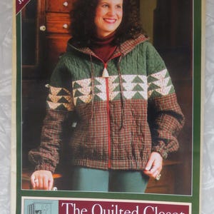 May include: A sewing pattern envelope for a Hooded Jacket #101 by The Quilted Closet. The cover features a quilted jacket with a green upper section, a cream band with green tree patterns, and a red and green plaid lower section and sleeves.