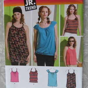 May include: A sewing pattern for a girls' top with a variety of styles. The pattern includes a sleeveless top with a scoop neck, a short-sleeved top with a scoop neck, and a sleeveless top with a scoop neck and a ruffle trim. The pattern is from Simplicity and is for sizes 3/4-9/10.