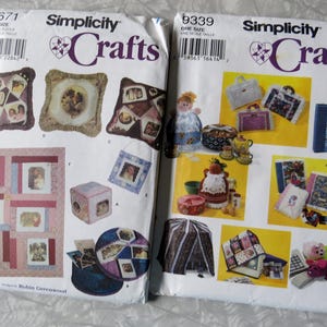 May include: Two Simplicity Crafts sewing pattern packets. One packet features photo frame pillows and a photo quilt. The other packet features various craft projects, including a doll, purses, and a book-shaped box.