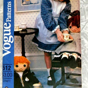 May include: A Vogue Patterns craft envelope 512 featuring an illustration of a child in a blue plaid dress with a white apron serving tea to a doll, while another doll with orange hair sits nearby wearing a black jacket with a white sailboat emblem.