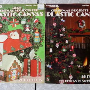 May include: Two Leisure Arts craft booklets titled More Christmas Projects for Plastic Canvas Leaflet 194 and Christmas Projects for Plastic Canvas Leaflet 153. The covers feature colorful photographs of various holiday-themed plastic canvas items.