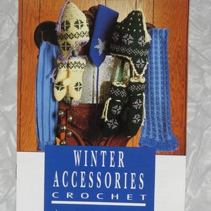 May include: A crochet pattern booklet titled The Pattern Library Winter Accessories Crochet by Herrschners Vol. 2 #17. The cover features a photograph of crocheted winter items including hats, mittens, and scarves in yellow, blue, and dark green.