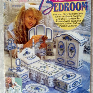 May include: A craft pattern for a Fashion Doll Dream Home bedroom set. The cover features a young girl with a doll and the finished plastic canvas furniture. The set includes a bed, wardrobe, and other accessories.