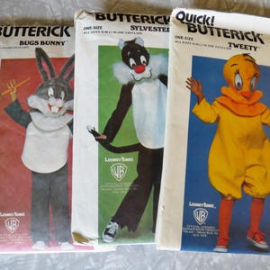 May include: Three vintage Butterick sewing pattern envelopes featuring Looney Tunes characters. The patterns include Bugs Bunny, Sylvester, and Tweety Bird costumes. The envelopes are white with colorful illustrations.