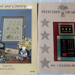 May include: Two cross-stitch pattern books, one titled "God and Country" with a patriotic theme and the other titled "Stitches from the Heartland" with a Christmas theme. Both books feature a variety of cross-stitch patterns.