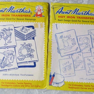 May include: Two vintage Aunt Martha's Hot Iron Transfers packages. One features kitchen designs, the other cross-stitch dishes. Both have yellow backgrounds with blue and white illustrations and text. Each design is good for several stampings.