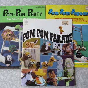 May include: Three vintage craft books: "Pom-Pon Party", "Pom Pom Parade", and "Pom Pom Pageant". The covers feature colorful pom-pom creations, including animals and toys. The books are in good condition, with text and illustrations.