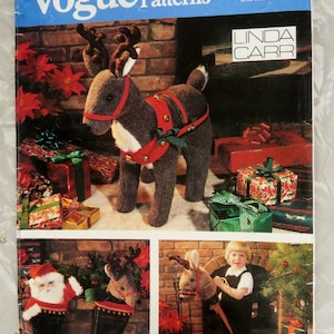 May include: A Vogue Patterns sewing pattern envelope, number 641, for a Linda Carr reindeer craft project. The cover features a brown plush reindeer with a red harness and bells, surrounded by wrapped gifts and a child with a reindeer stick toy.