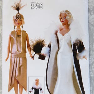 May include: Vogue Craft sewing pattern 7162 featuring doll fashions. The pattern includes images of dolls in flapper-style dresses and a long white gown with a black and white coat. The pattern is designed by Linda Carr.