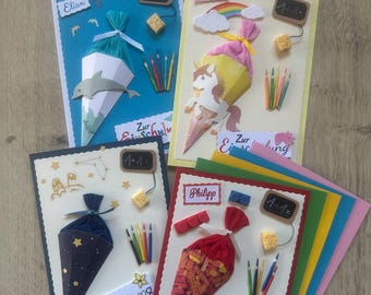 May include: Four handmade greeting cards for school enrollment, each featuring a 3D paper cone, miniature colored pencils, a small chalkboard with math equations, and the text Zur Einschulung. The cards display themes of dolphins, unicorns, space, and building blocks with personalized name tags.
