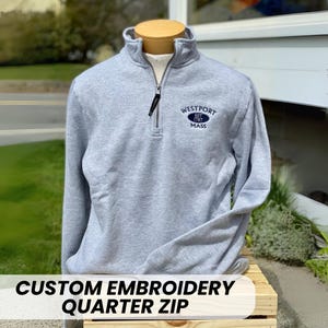 May include: A gray quarter-zip sweatshirt with a navy blue embroidered logo that says "Westport Est. 1787 Mass".