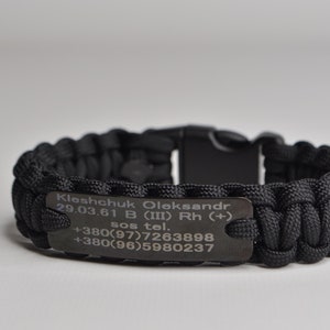 May include: Black paracord bracelet with a metal tag engraved with the text "Kleshchuk Oleksandr 29.03.61 B (III) Rh (+) sos tel. +380(97)7263898 +380(96)5980237".