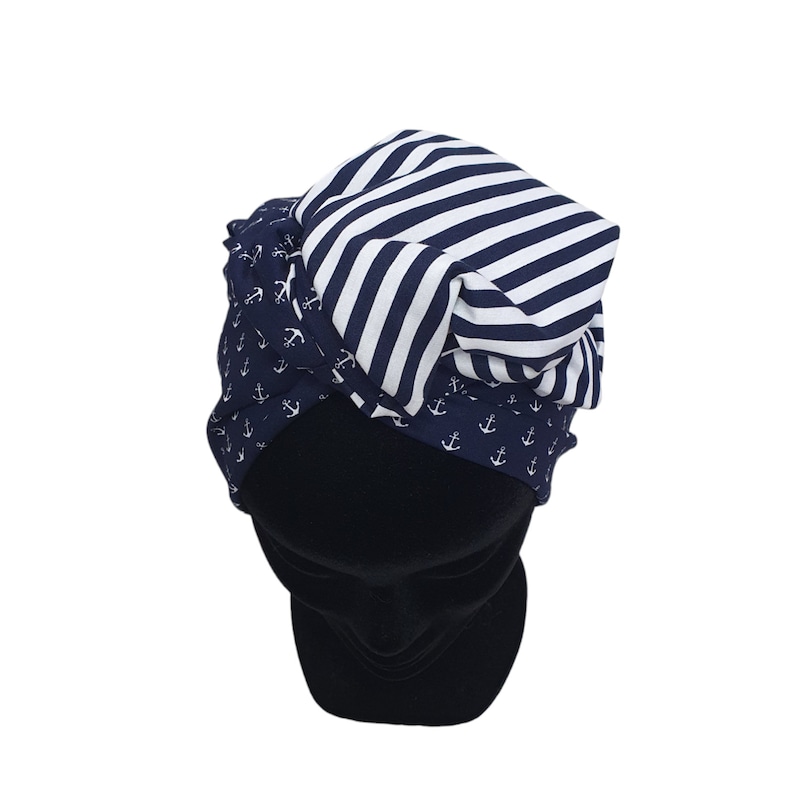 Puede incluir: Un sombrero de tem&aacute;tica n&aacute;utica con un dise&ntilde;o en capas. El sombrero presenta una tela azul marino con patrones de anclas blancas, una secci&oacute;n a rayas azul marino y blanco, y una base negra s&oacute;lida. El sombrero est&aacute; dise&ntilde;ado para ser usado en la cabeza.