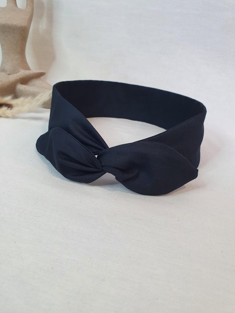 Puede incluir: Una diadema azul marino oscuro con un detalle de lazo anudado. La diadema est&aacute; hecha de una tela lisa y s&oacute;lida. El lazo est&aacute; centrado en la diadema y est&aacute; dise&ntilde;ado para ser usado alrededor de la cabeza.