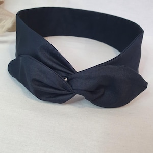 Puede incluir: Una diadema anudada azul marino. La diadema est&aacute; hecha de una tela suave y presenta un detalle de nudo retorcido en la parte delantera. La diadema est&aacute; dise&ntilde;ada para usarse alrededor de la cabeza y es de color s&oacute;lido.