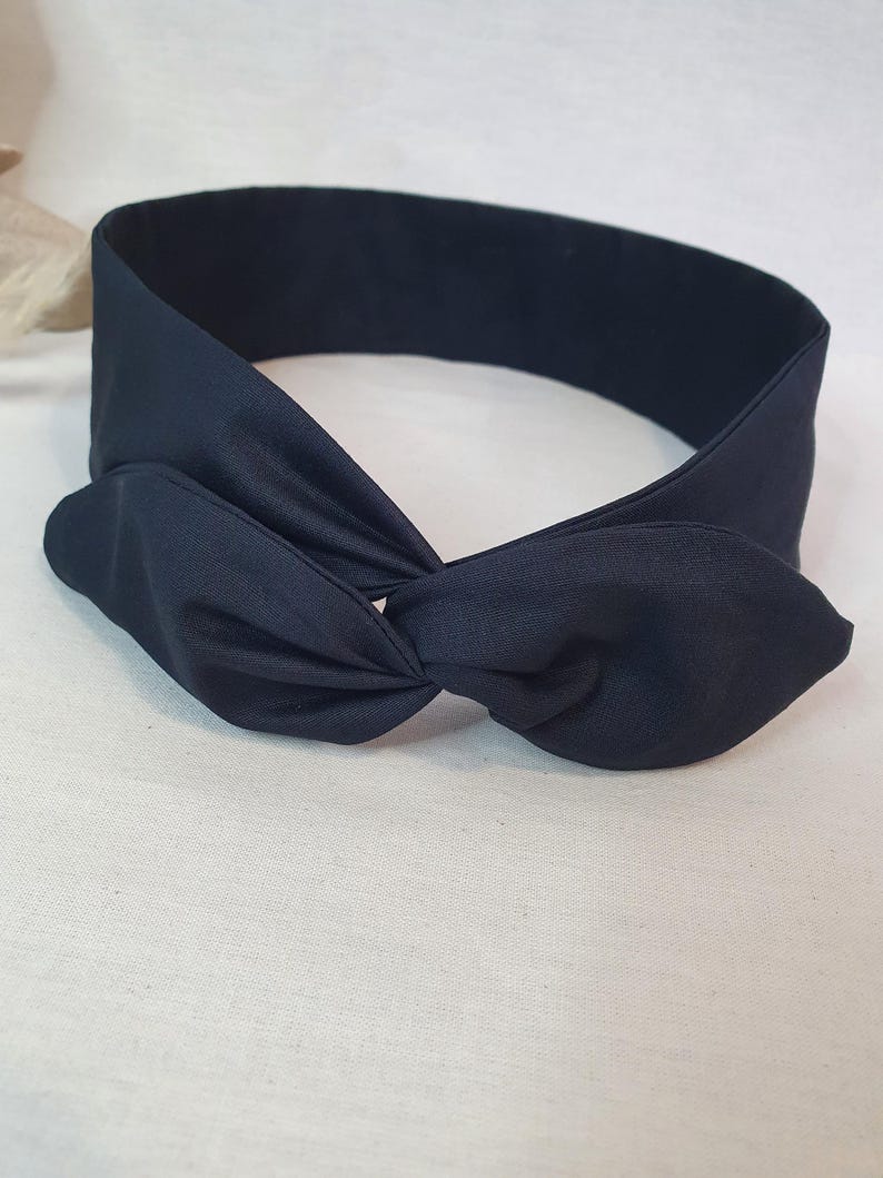 Puede incluir: Una diadema anudada azul marino. La diadema est&aacute; hecha de una tela suave y presenta un detalle de nudo retorcido en la parte delantera. La diadema est&aacute; dise&ntilde;ada para usarse alrededor de la cabeza y es de color s&oacute;lido.