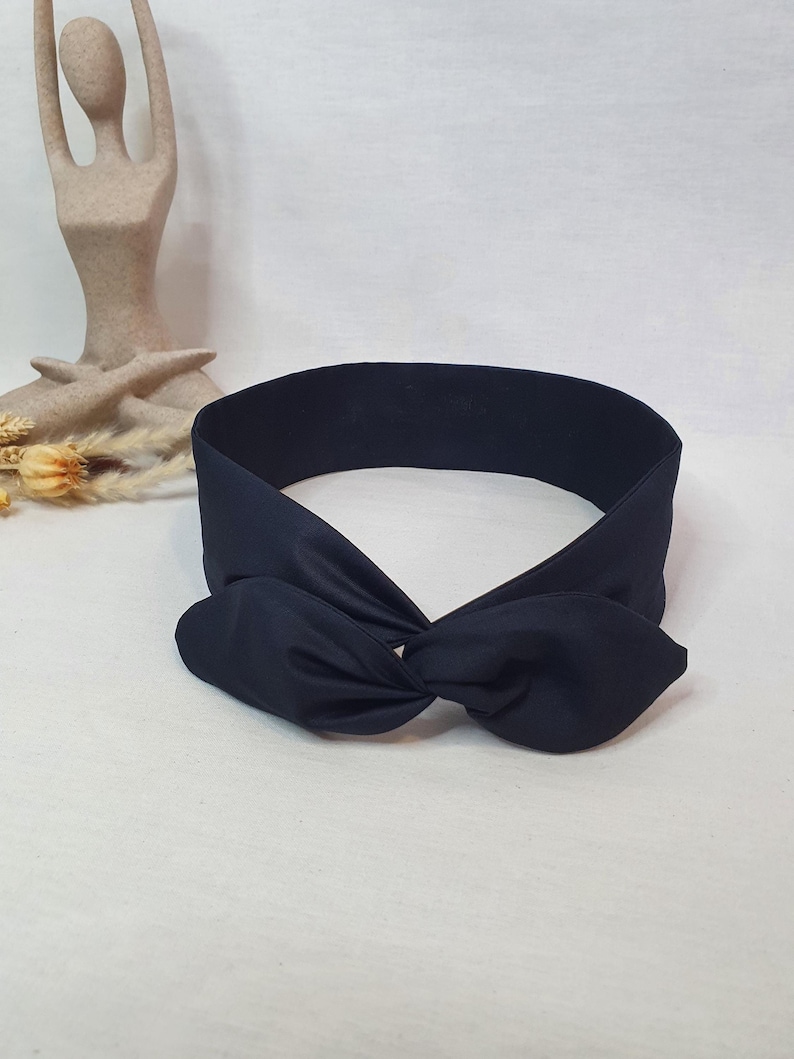 Puede incluir: Una diadema azul marino con un detalle de lazo anudado. La diadema est&aacute; hecha de una tela suave y est&aacute; dise&ntilde;ada para usarse alrededor de la cabeza. El lazo est&aacute; centrado en la diadema.