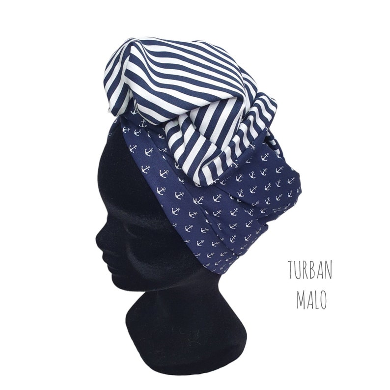 Puede incluir: Un turbante azul marino y blanco con un tema n&aacute;utico. El turbante presenta un patr&oacute;n de anclas blancas sobre un fondo azul marino y una secci&oacute;n de rayas blancas y azul marino. El texto "TURBAN MALO" es visible.