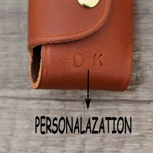 May include: A brown leather key holder with a gold button and the initials "DK" embossed on the front. The key holder is a great way to personalize your keys.