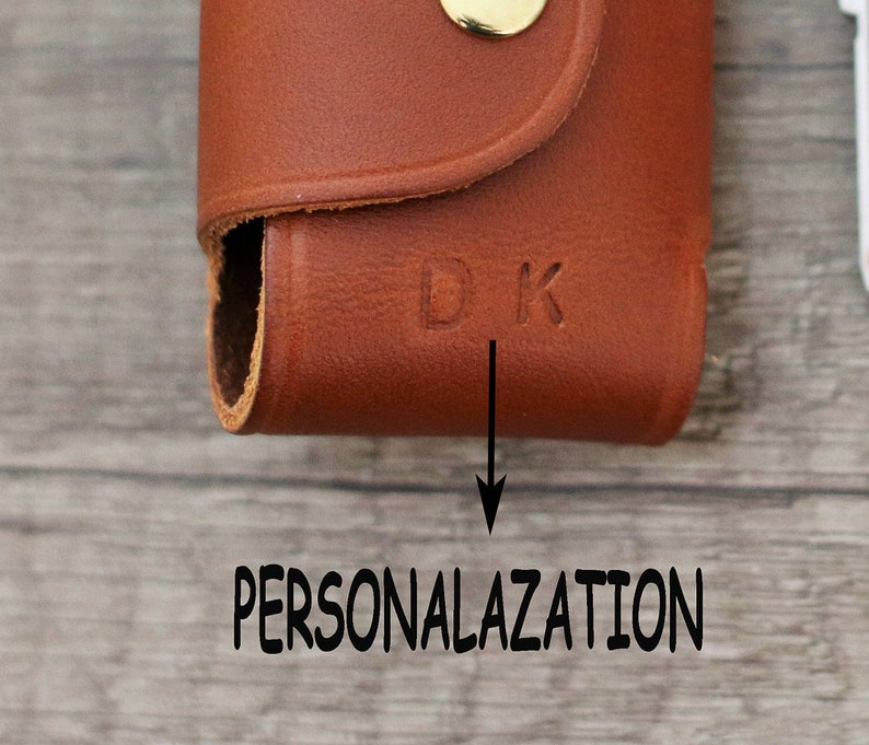 May include: A brown leather key holder with a gold button and the initials "DK" embossed on the front. The key holder is a great way to personalize your keys.