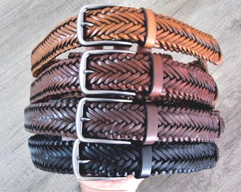 May include: A stack of four braided leather belts in various shades of brown and black. Each belt features a silver-colored rectangular buckle. The belts are arranged from light to dark, showcasing the different color options.