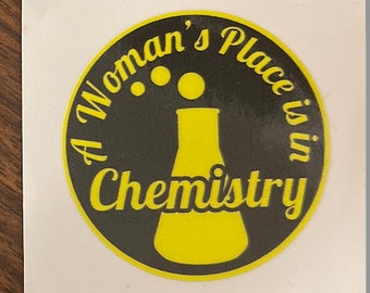 May include: A black and yellow round sticker with the text "A Woman's Place is in Chemistry" and a yellow beaker with three yellow dots above it.