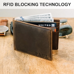 May include: A brown leather wallet with RFID blocking technology. The wallet is open and shows cash and a credit card with the word "UNITED" on it. The wallet is personalized with the name "PAUL" on the bottom.