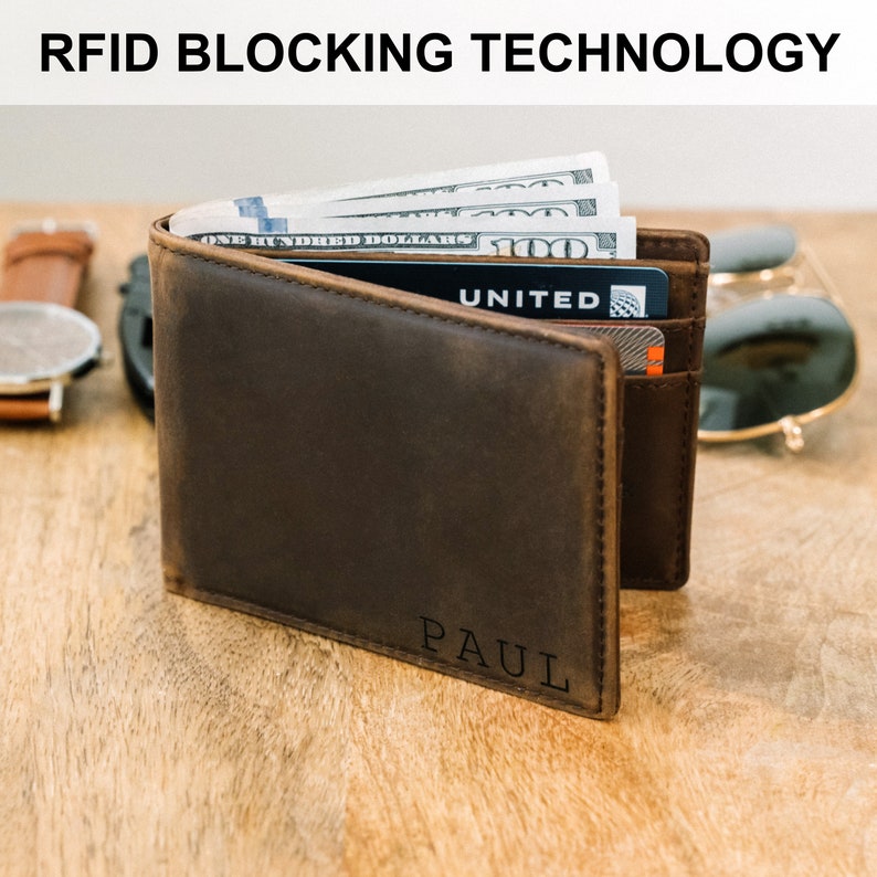 May include: A brown leather wallet with RFID blocking technology. The wallet is open and shows cash and a credit card with the word "UNITED" on it. The wallet is personalized with the name "PAUL" on the bottom.