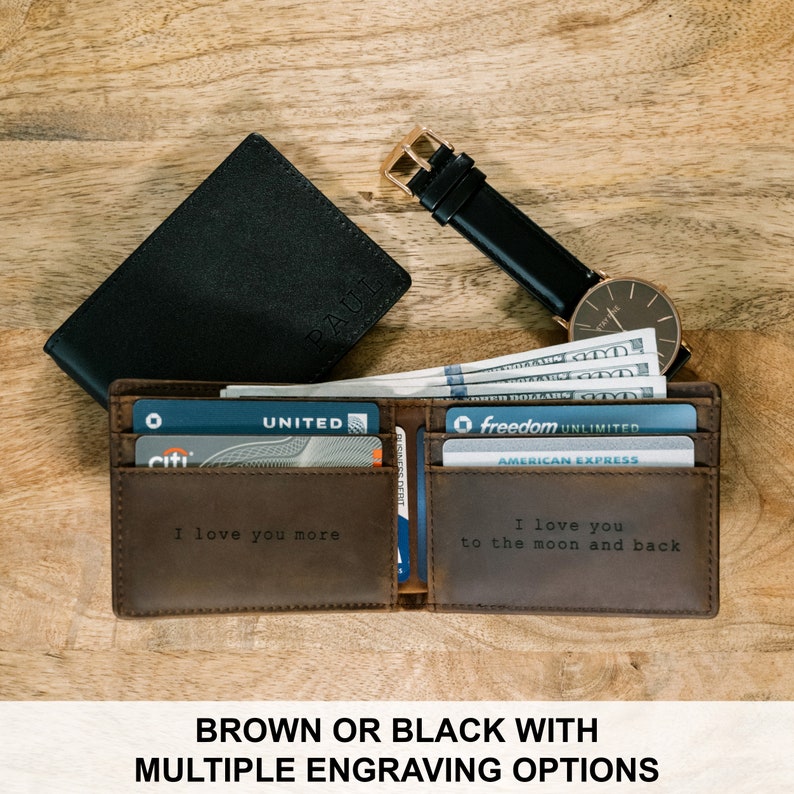 May include: Brown leather wallet with a personalized engraving that says "I love you more". The wallet is open and has credit cards and cash inside. The wallet is on a wooden surface.