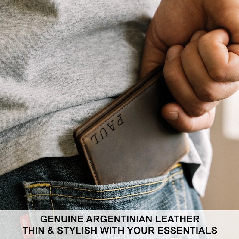 May include: A brown leather wallet with the name "PAUL" embossed on the front. The wallet is being held in a back pocket of a pair of blue jeans.