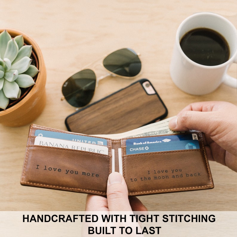 May include: A brown leather wallet with a personalized message that reads "I love you more" on one side and "I love you to the moon and back" on the other side. The wallet is open and has credit cards and cash inside.