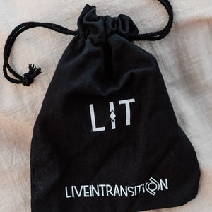 May include: A black drawstring bag with the word "LIT" and the text "LIVEINTRANSITION" printed in white.