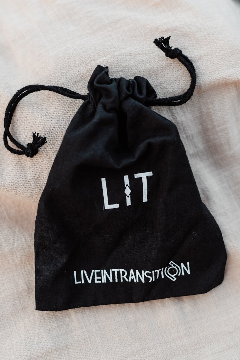 May include: A black drawstring bag with the word "LIT" and the text "LIVEINTRANSITION" printed in white.