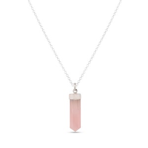 K&ouml;nnte beinhalten: Eine silberne Kettenkette mit einem rosa Kristall-Anh&auml;nger in Form einer Spitze.